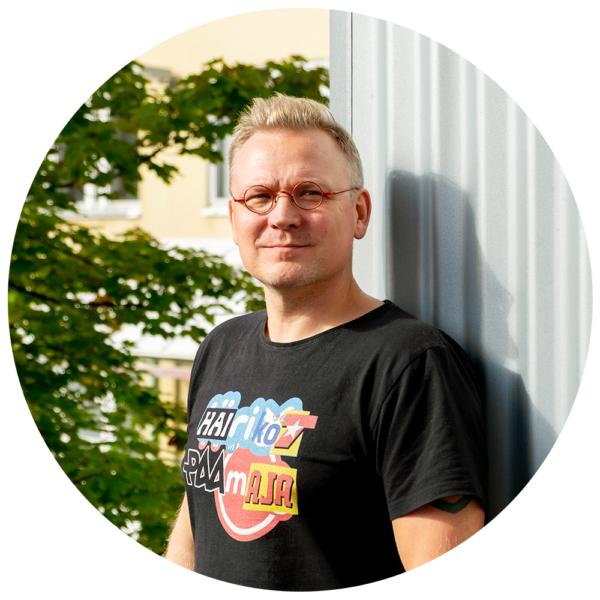 Tamminen katsoo kameraan. Taustalla peltiseinä ja kaupunkiluontoa.