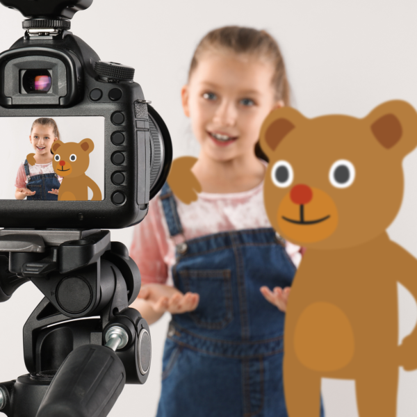 Lapsi puhuu studiossa kameralle, digitaalisesti tuotettu nalle vieressä.