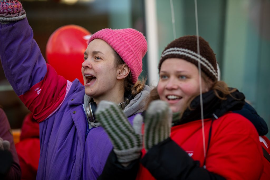 Kaksi mielenosoittajaa, toinen taputtaa ja toinen hurraa.