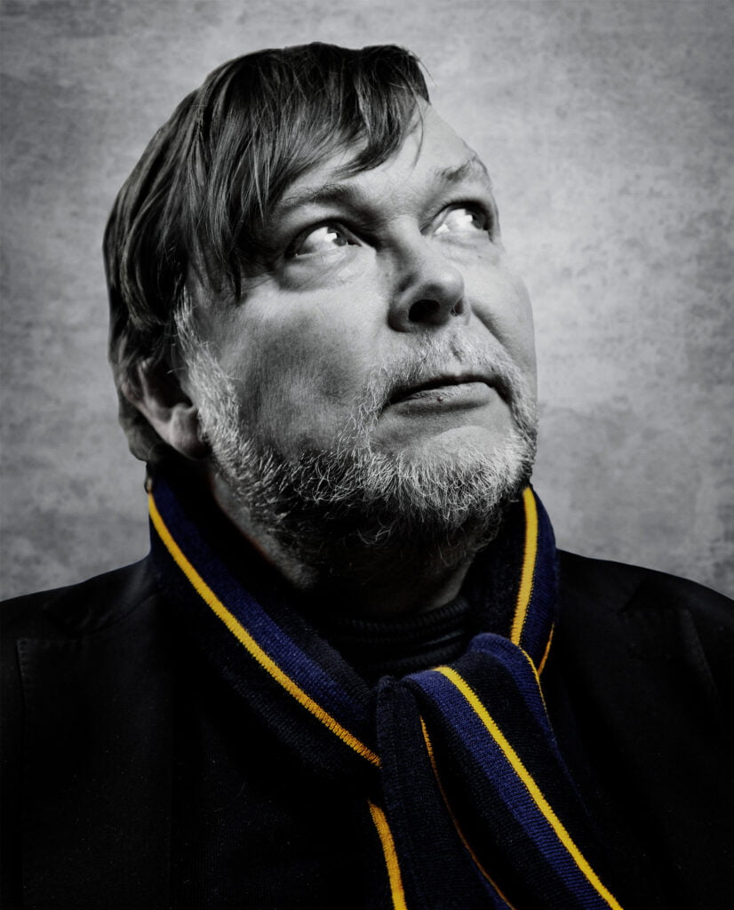 Mustavalkoinen valokuva Markus Leikolasta, kaulahuivi sini-keltainen.