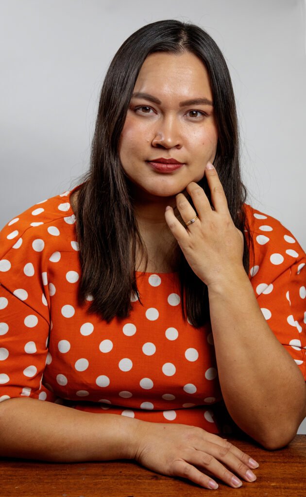 Alice Jäske katsoo kameraan, taustalla harmaa seinä.