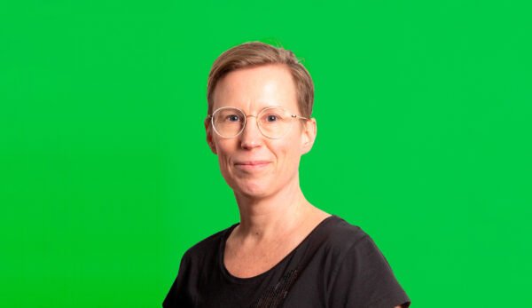 Johanna Ruohonen katsoo kameraan hymyillen, vihreä tausta.