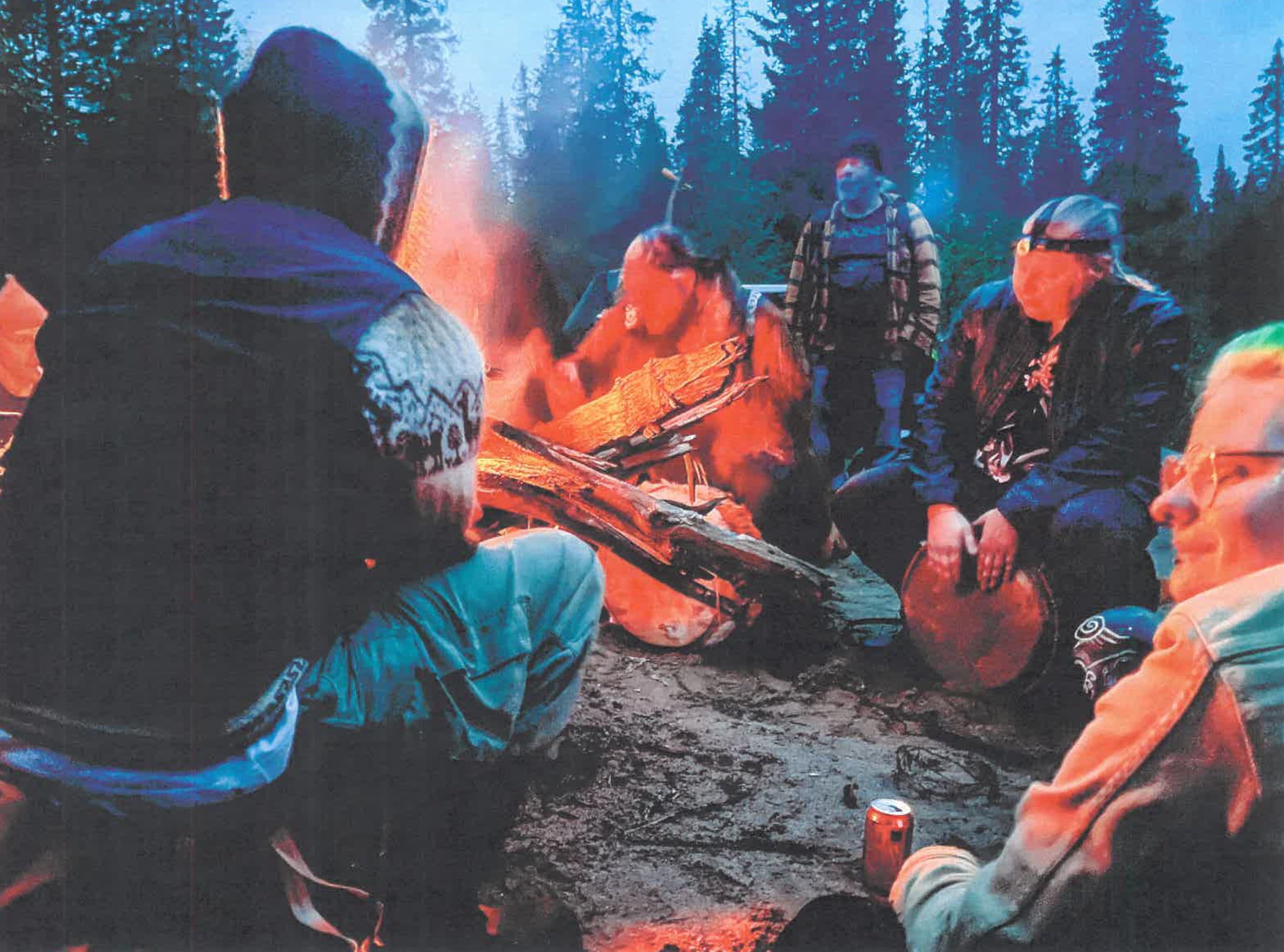 Ihmisiä kerääntynyt nuotion ympärille ja soittaa rumpuja.
