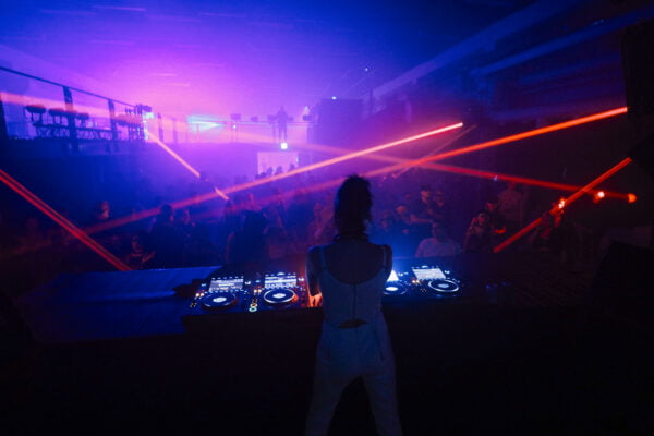 Laaja kuva hämärästä klubista, kuvattu yleisöä dj-pöydän takaa.